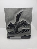 Front view of the soapstone carving depicting a bird midway through takeoff, with fine details and texture.