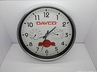 Full front view of DAYCO branded wall clock with thermometer and hygrometer and 50th anniversary logo.