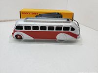 Side view of DINKY Toys Atlas Autocar Isobloc bus model with original yellow box in background.