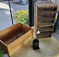 Wooden wine crate, pie shelf carrier, and vintage tin match holder on table with outdoor background
