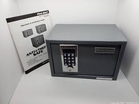 Front view of the First Alert digital key safe with keypad and accompanying user manual.