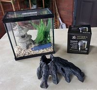Mini aquarium setup with gravel, artificial plant, stone pagoda, tree stump decoration, and boxed power filter