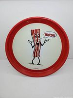 Photo of the full round vintage tin tray with red rim and cartoon bacon character with 'BACON' speech bubble.