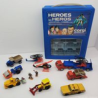 Front view of the vintage CORGI die-cast vehicle set with all vehicles and figurines arranged in front of the blue plastic Heroes carry case.
