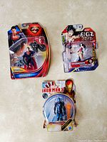 Three sealed action figures including Superman with Batcycle, Wonder Woman, and Iron Man 3 figure.