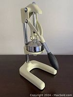 Front view of cream-colored Cilio manual citrus press showing lever with black handle.