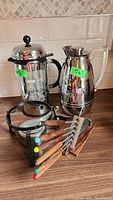 Wide photo showing the Bodum French press, Thermos coffee pot, fondue pot base, and six fondue forks with colored tips.
