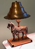 Front view of a copper Art Deco style lamp with a horse figurine base and tiered copper shade.