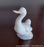 Side view of the white porcelain duck figurine showing the smooth glossy finish and feather details on the wings and tail.