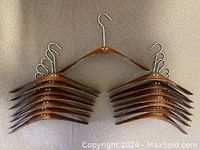 15 Pilot bent wood coat hangers arranged in two stacks with one hanger displayed on top, showing swivel hooks and wood finish.