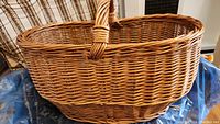 Side view of the oval wicker basket with handle showing weaving detail and color.