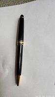 Full length view of black resin pen with gold tip and trim on white background