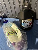 Photo of Basketball Jones socks sealed in plastic packaging next to a black Bubba Trailblazer water container with lid on a blue surface.
