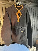 Front view of Carhartt mens size XL black sherpa fleece pullover jacket with mustard tan snap button placket and matching trim.