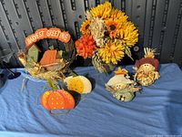 Photo of fall decoration lot showing Harvest Greeting sign, floral arrangement, pumpkin decorations, and scarecrow figurines on blue surface