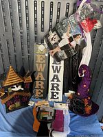 Lot items arranged to show Halloween decorations and costume pieces including signs, hat, and packaged costume.