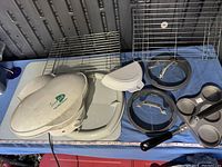 White George Foreman electric grill with various kitchen trays and metal cooling racks arranged on table