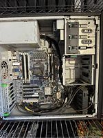 Interior view of one desktop computer tower showing motherboard, power supply unit, PCI slots, cables, and empty drive bays