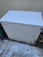 Front view of white Honda chest freezer showing weathered top lid and front panel with visible wear and some rust spots near handle.
