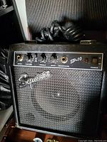 Front view of Squier SP-10 guitar amplifier showing controls, logo, and power cord on top.