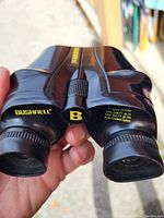 Close-up of Bushnell branding and specs on binoculars showing 7x/15x zoom and fully coated optics.