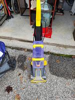 Full view of upright Bissell vacuum showing yellow handle and purple clear debris container.