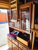 Photo showing upper glass door section of the wooden china cabinet with white knobs and wooden slats attached.
