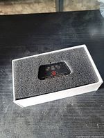 Top view of the iCar device inside foam packaging inside the box showing black device with indicator lights and power button.