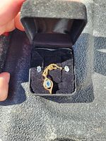 Photo of a gold-tone chain necklace with an oval blue gemstone pendant, and matching blue gemstone stud earrings set in a black jewelry box