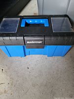 Front view of a blue and black Mastercraft plastic tool box with a top handle, latch, and two clear compartments on the lid.