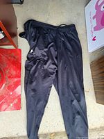 Black Under Armour athletic pants laid flat showing front side with logo visible on thigh.
