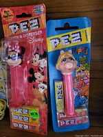 Photo of two unopened original PEZ candy dispensers: Minnie Mouse and Muppets characters, with candy packs inside blister packaging.