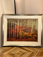 Frontal view of autumn forest painting showing canvas imagery and silver frame
