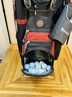 Lower compartment of travel golf bag filled with white golf balls, showcasing size and condition.