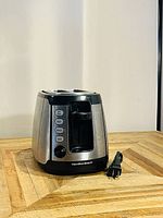Side and front views of the Hamilton Beach 2 slice toaster showing the buttons and dial control with attached power cord.
