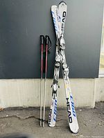 Full view of two Head C160 skis joined and ski poles leaning against the wall, showing overall condition and completeness