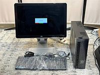 HP desktop PC tower, monitor, keyboard, mouse, and cables arranged on a carpeted floor. Monitor is on, showing a ready screen message.