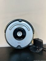 Front view of iRobot Roomba 630 on charging dock base, showing central clean button and status indicators