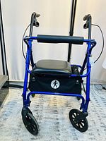 Front view of blue aluminum walker showing padded seat, loop brake handles, and front casters.