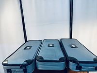 Three grey, zippered carrying bags for banner stands placed side by side horizontally, showing the top of the bags with handle slots visible.