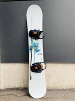 Top view of the Burton snowboard showing mounted black bindings with orange details and geometric blue design on the deck.
