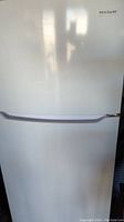 Closed front view of white Frigidaire refrigerator showing integrated handle and minor surface scratches.