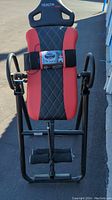 Front view of the Health Gear inversion table with black and red padded upholstery showing the full frame and headrest with logo.