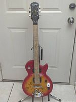 Full front view of guitar showing finish, body shape and protective paper on fretboard