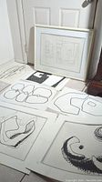 Multiple unframed and one framed black-and-white abstract lithographs by Serge Chermayeff arranged on floor and against wall