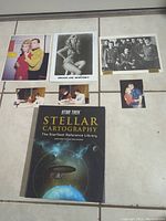 Lot overview showing six photographs including signed and unsigned images of Star Trek cast members and the Stellar Cartography book arranged on a tiled floor.