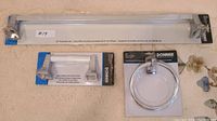 Full view of the three packaged chrome bathroom accessories: towel bar, paper holder, towel ring.