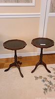 Pair of vintage octagon-shaped wine side tables with black and gold decorated tops in a room setting on a light colored floral patterned rug