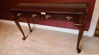Full front view of the Bombay Company console table showing the three drawers with brass handles and cabriole legs.