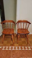 Two maple wooden chairs side by side showing front and side views on parquet flooring.